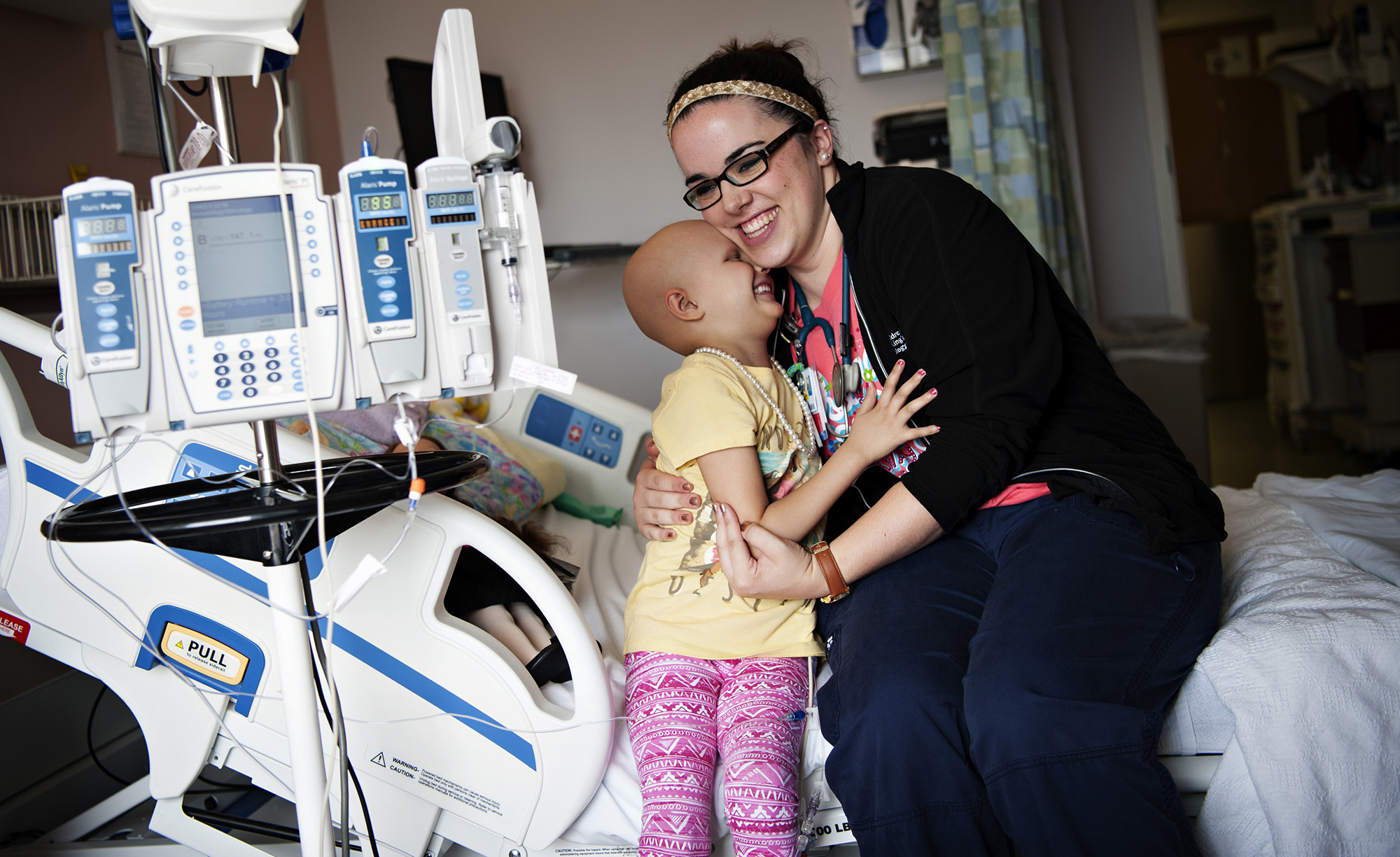 Nurse laughing with young female patient in her room.
