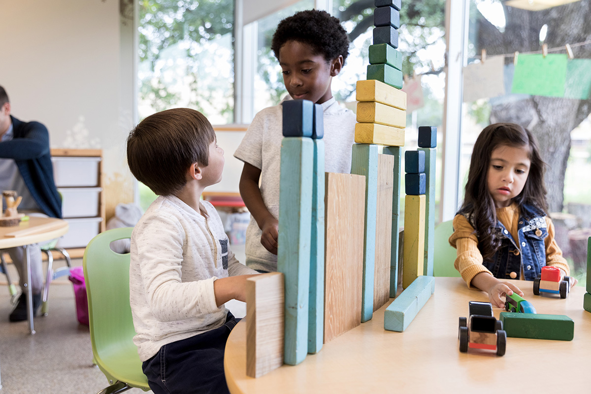 Two preschool boys talk while playing with blocks.