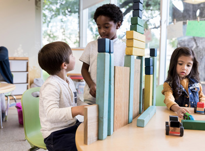 Two preschool boys talk while playing with blocks.
