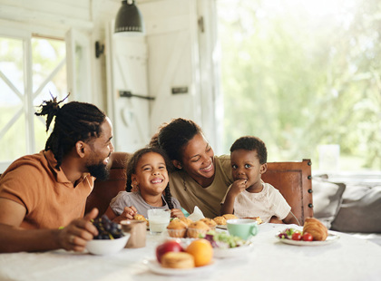 Happy black family having breakfast at dining table.
