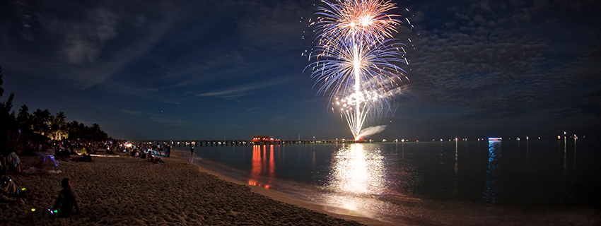 Fireworks over water on the horizon.