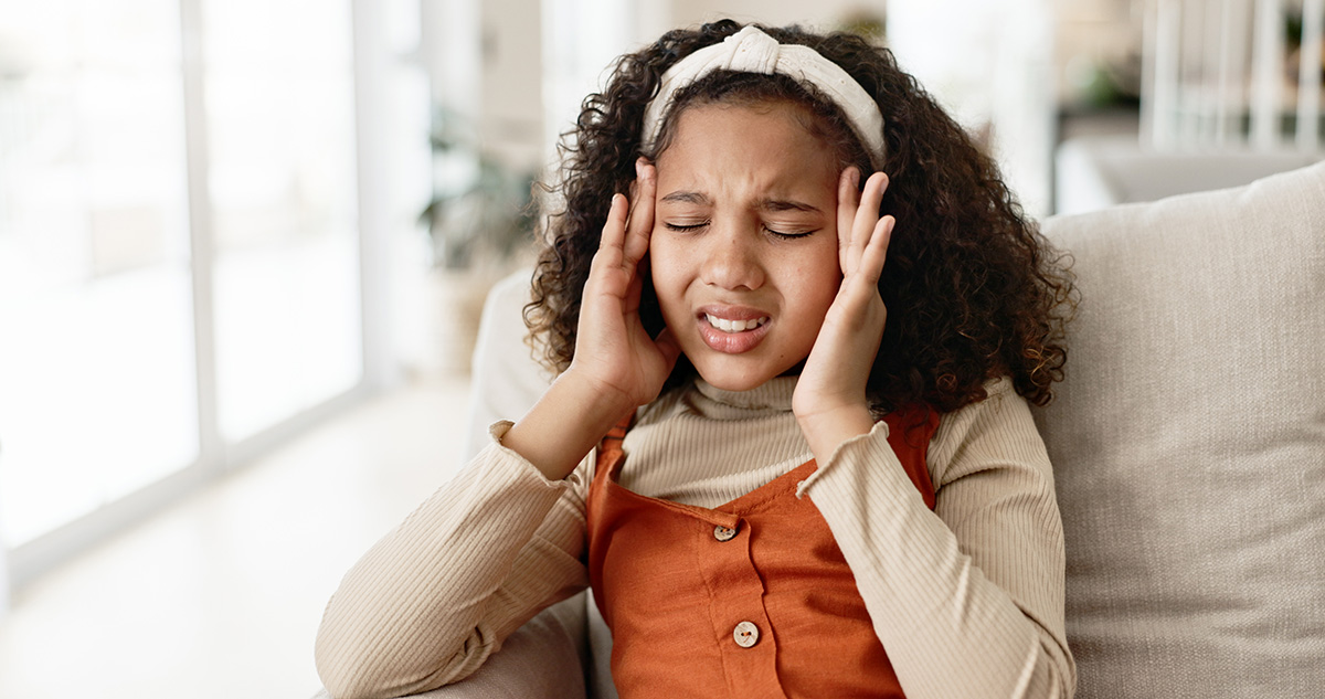 Young girl, headache and sofa with stress in anxiety, pain or distress for noise at home.