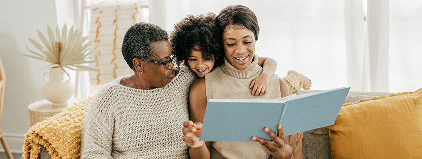 Grandmother, mother, and daughter look at photo album together.
