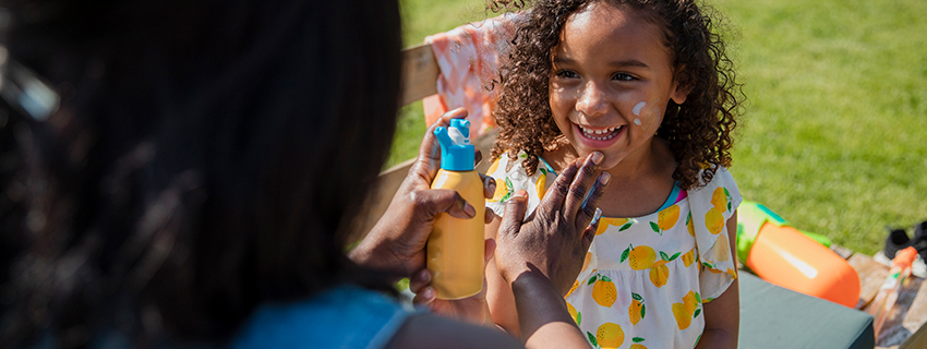Parent applying sunscreen to their child's face.