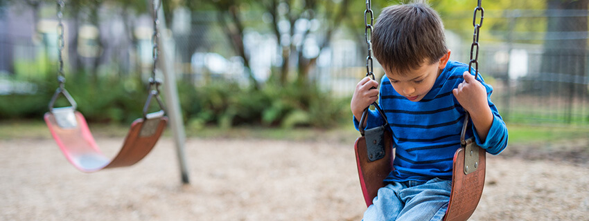 Young boy swinging by himself on playground