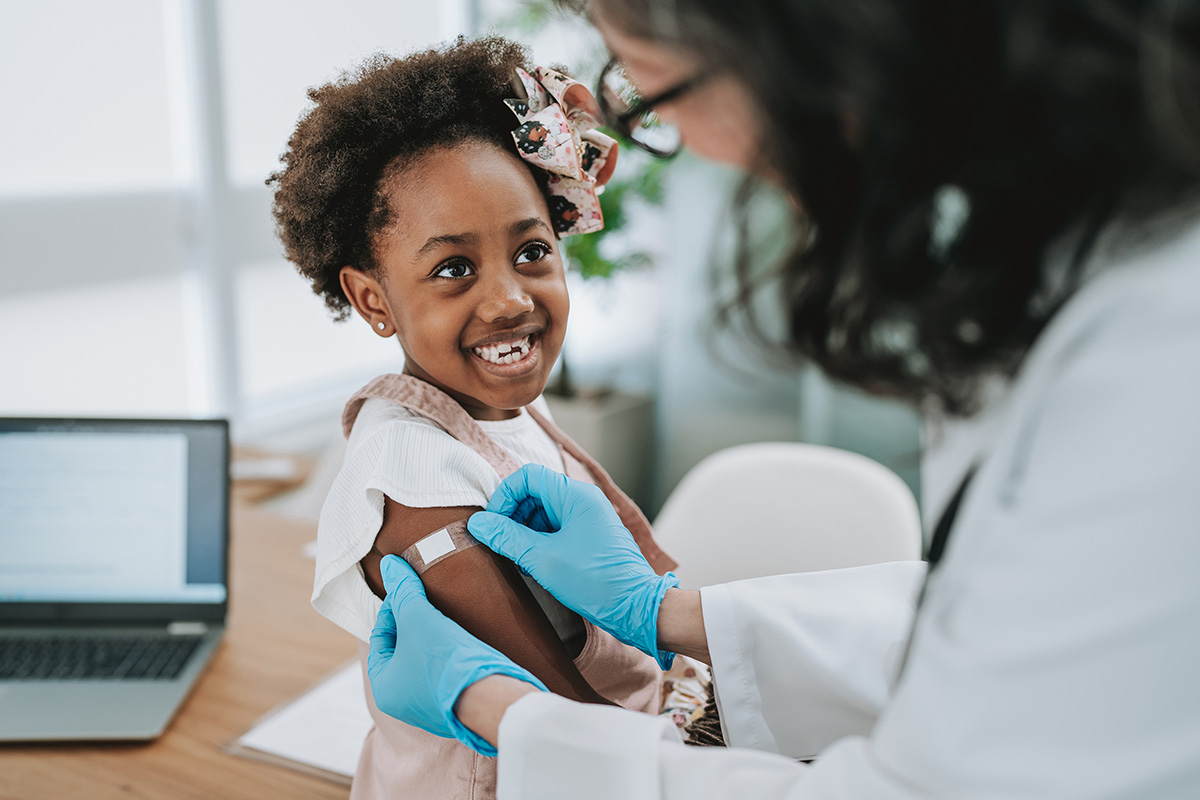 Doctor putting a bandage on a child's arm after getting a vaccine.