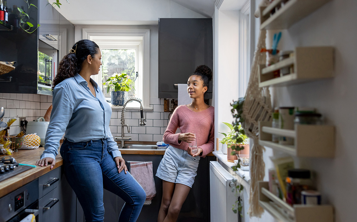 Mother and daughter having a conversation together in the kitchen.