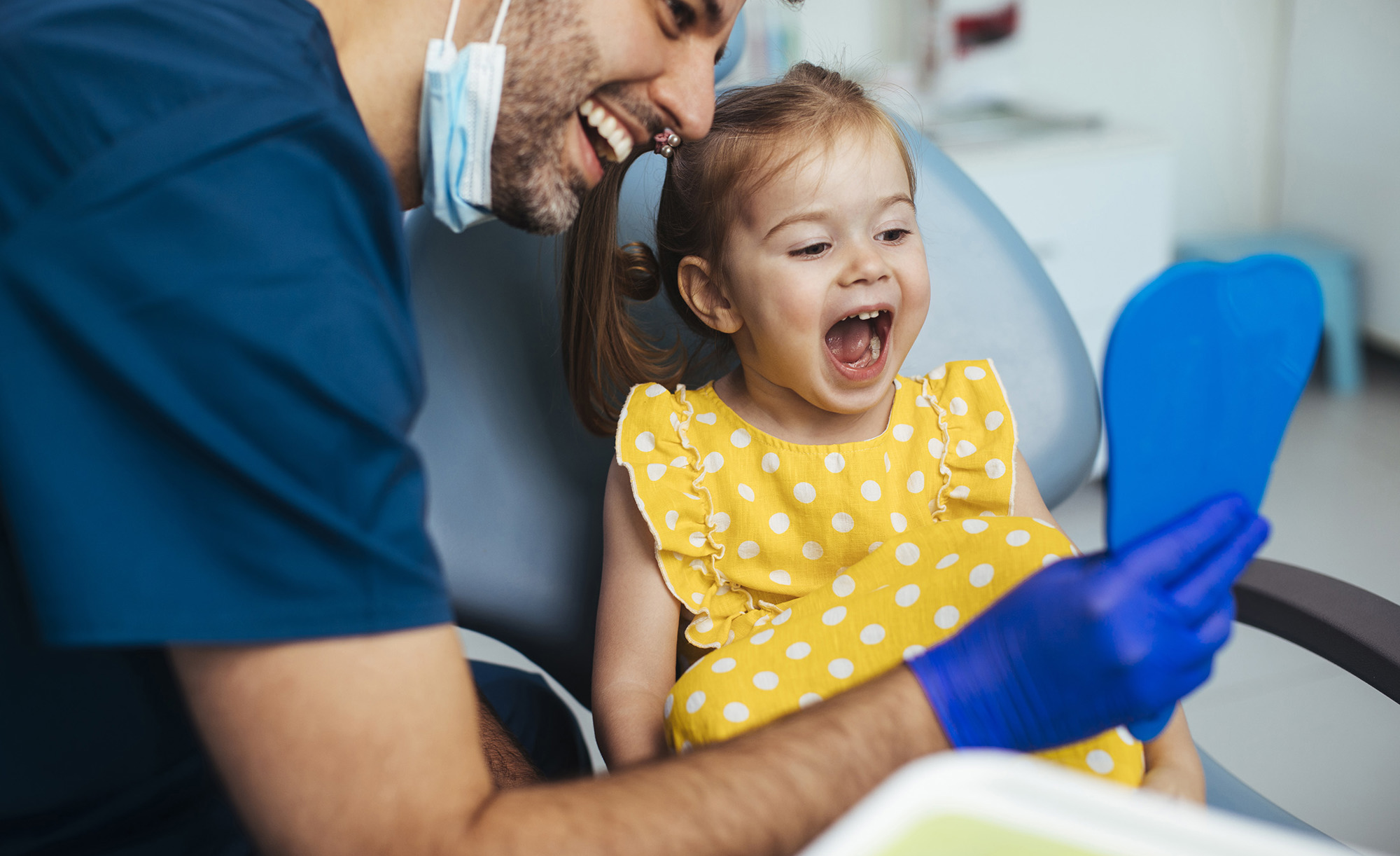 Young girl looking at a mirror after having a routine checkup at the dentist