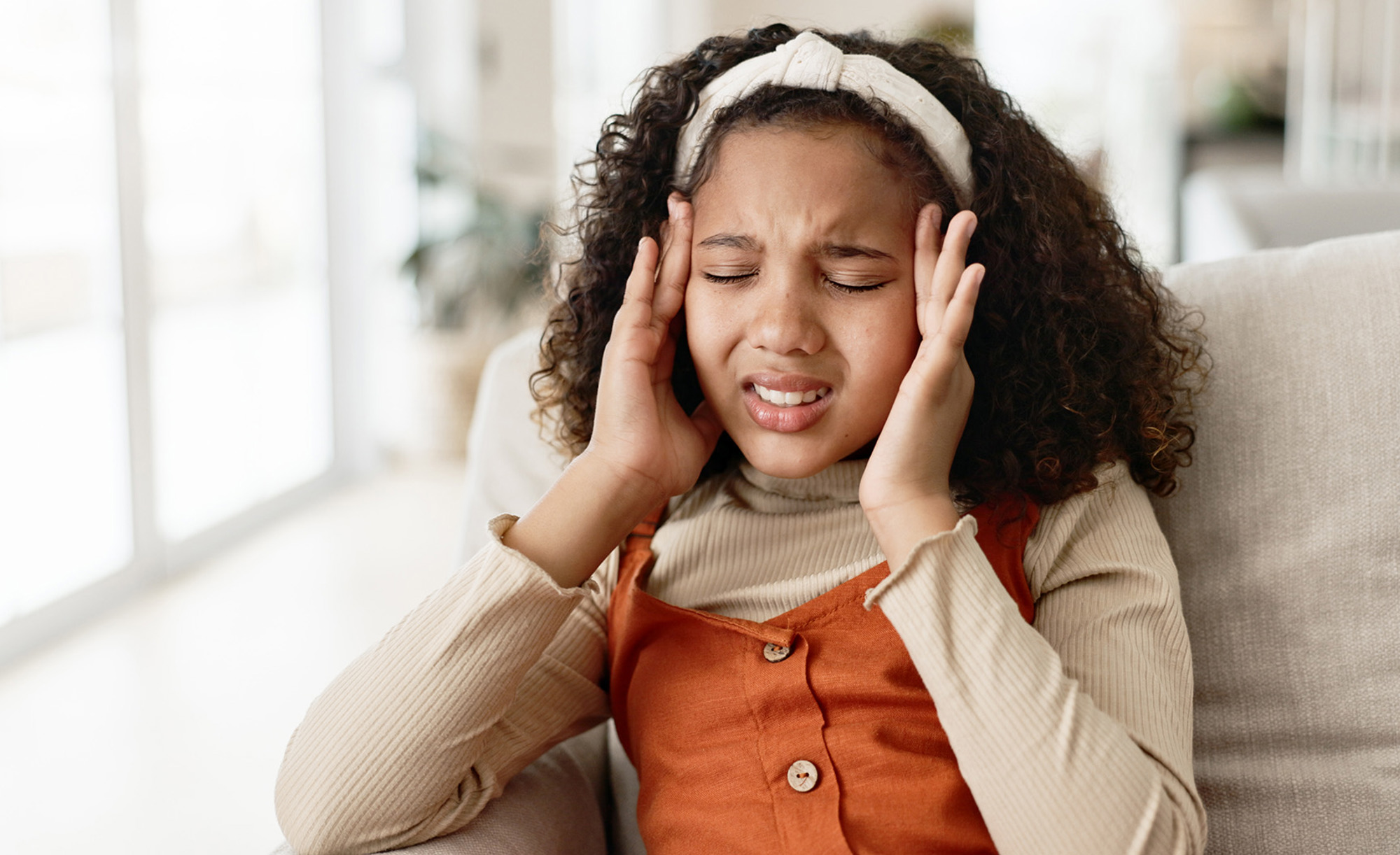 Teenage girl holding her head as if she has a headache. 