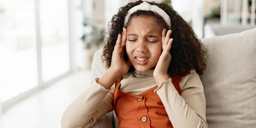Teenage girl holding her head as if she has a headache. 