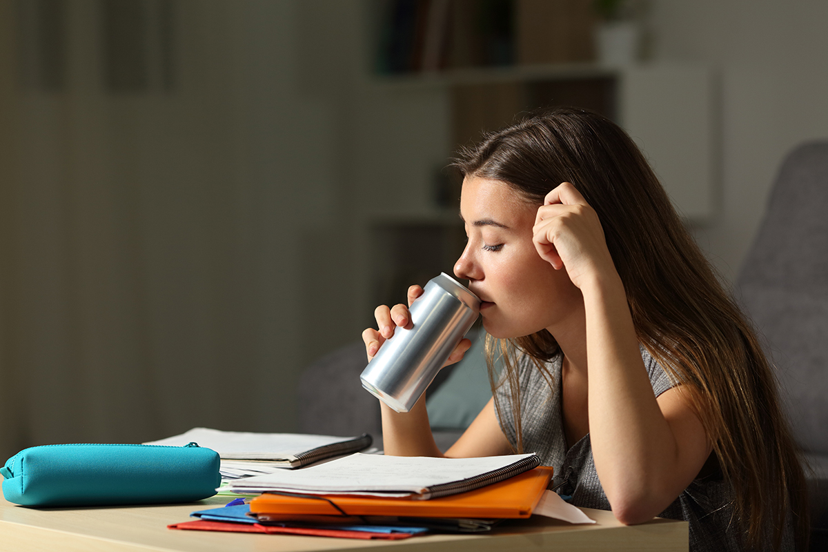 Teen studying while drinking an energy beverage 