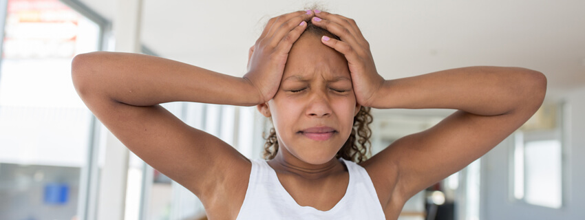 Teen holding her head in pain