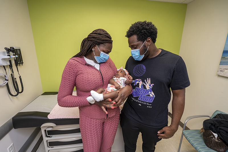 Samirah in her moms arms as both her mom and dad look lovingly at her.
