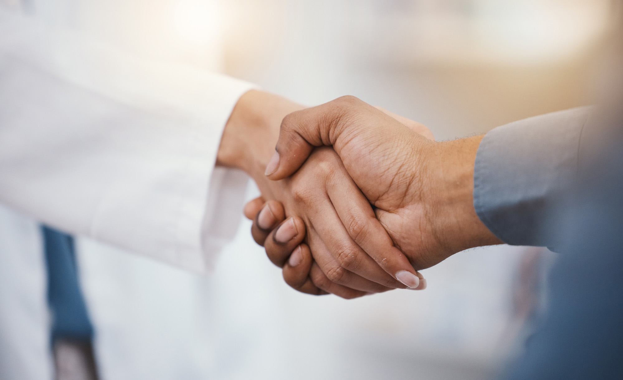 Doctor, patient and handshake in hospital thank you, welcome or greeting for medicine trust, help or medical consulting. Zoom, black man and shaking hands with pharmacy worker or healthcare employee