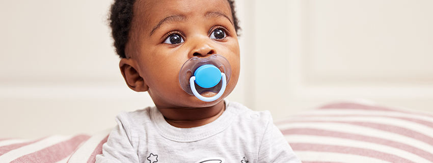 Cute baby with a pacifier in his mouth.