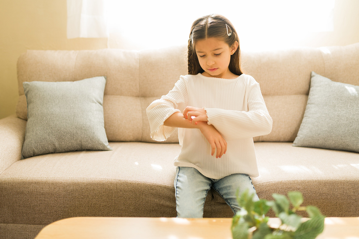 Young girl experiencing an itch on her skin, possibly a symptom of an allergy or dermatitis