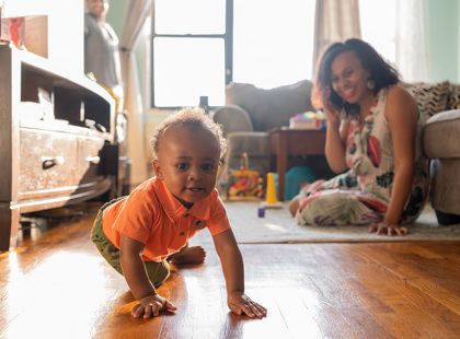 Baby crawling away as mom talks on the phone in the background.