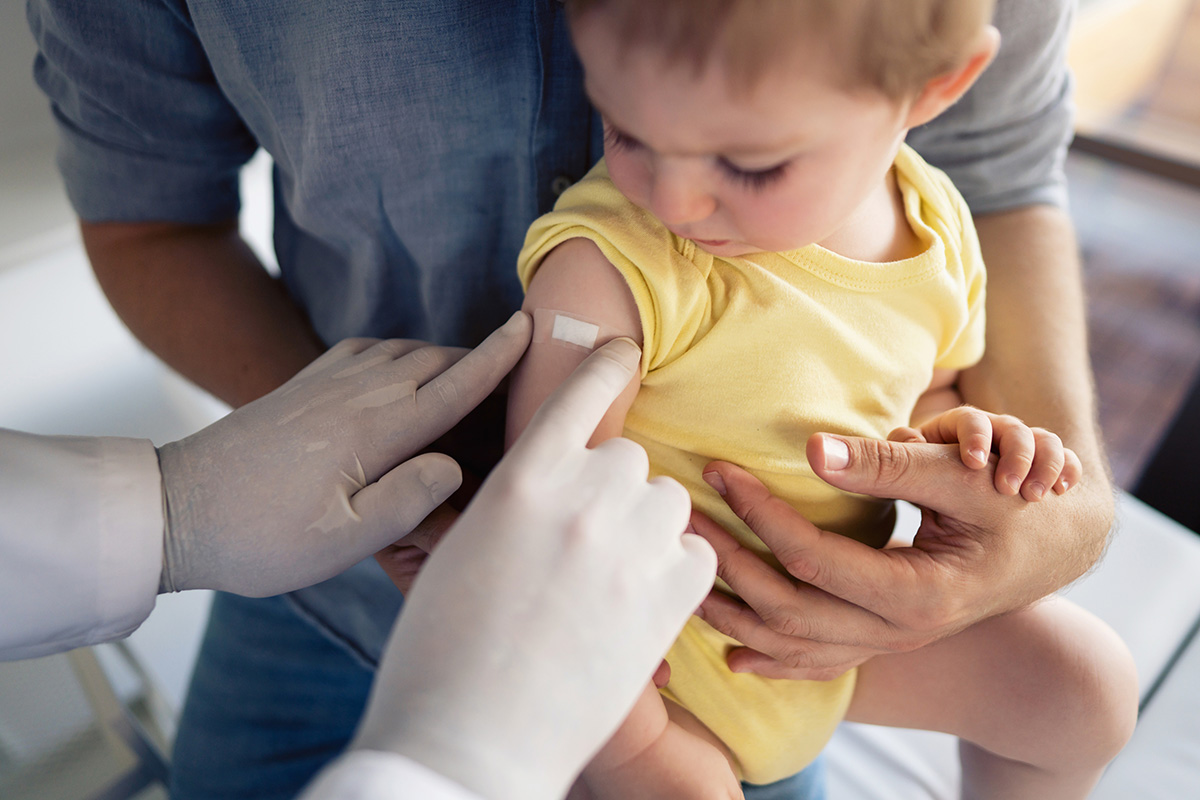 Nurse putting a bandage on a child who was just vaccinated.