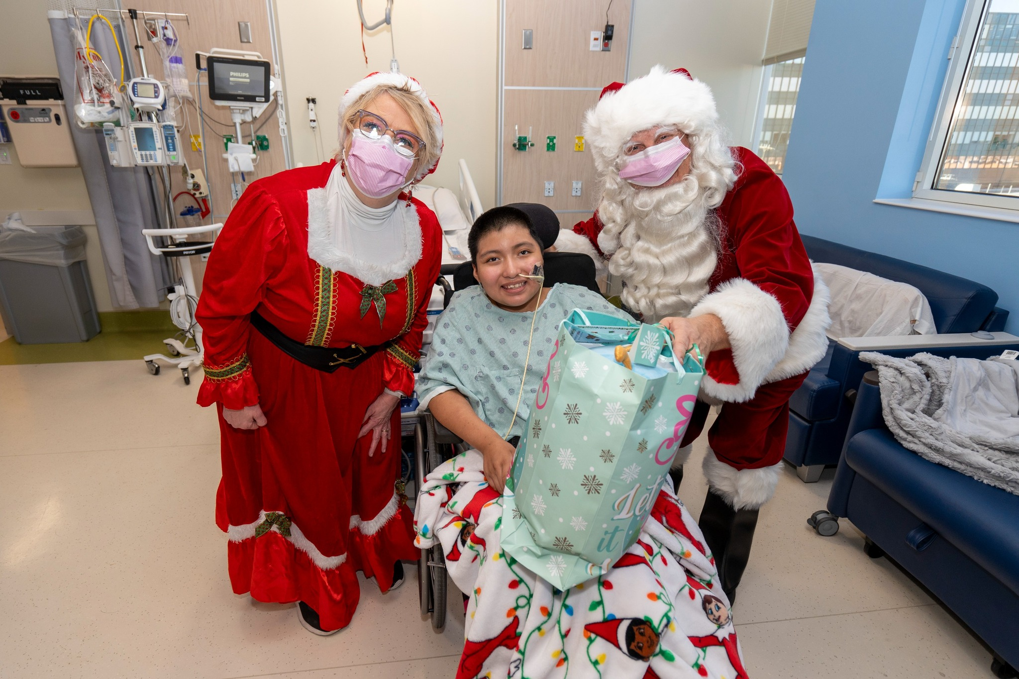 Santa and Mrs. Clause smile with a teen patient at CHKD.