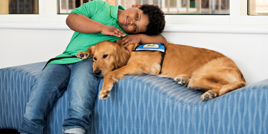Young boy, Eathan Freeman, with CHKD facility dog.