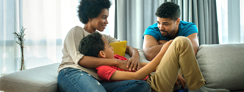 Mom and dad talk to son, who is lying in mom's lap.