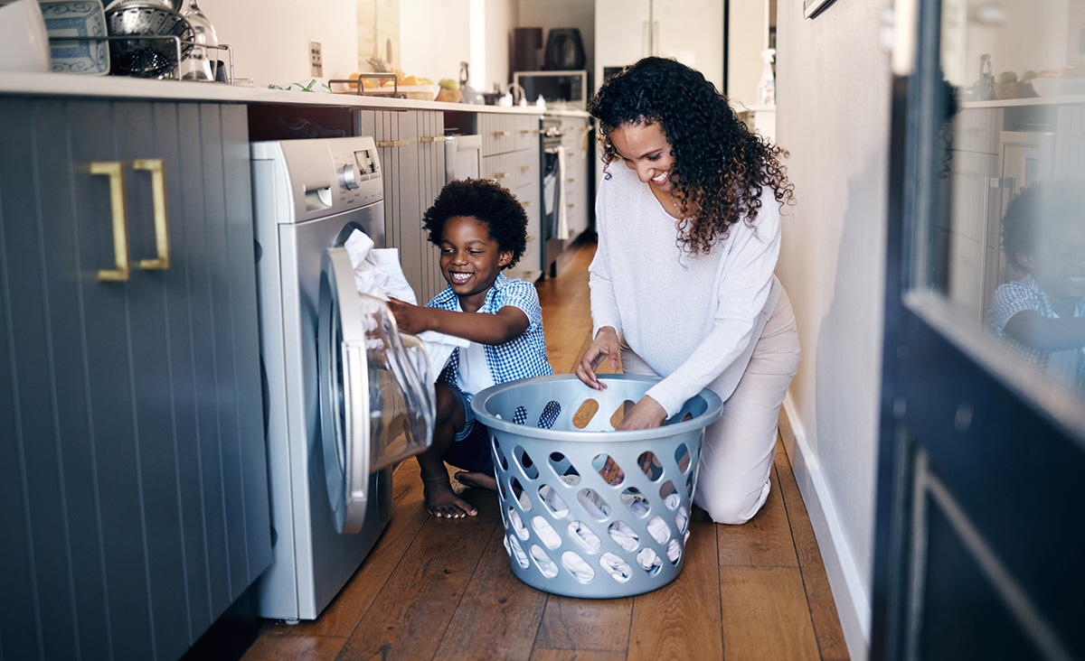 Young son helps his mom take the clothes out of the dryer.
