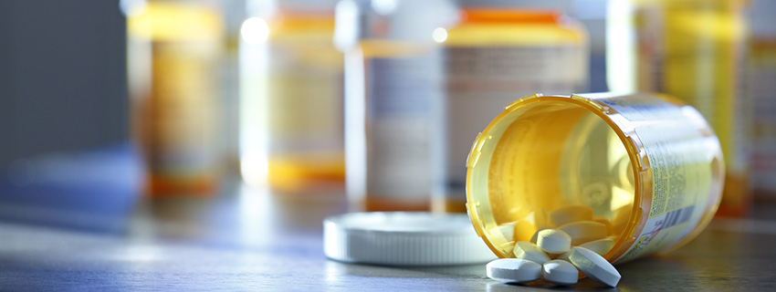 Bottle of prescription medication tipped over on a counter.