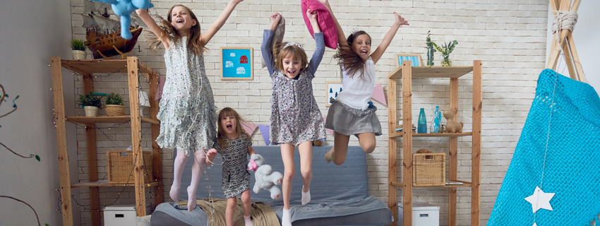 Group of four girls jumping on couch.