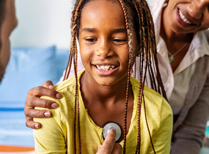 Young girl smiling during physical exam with doctor