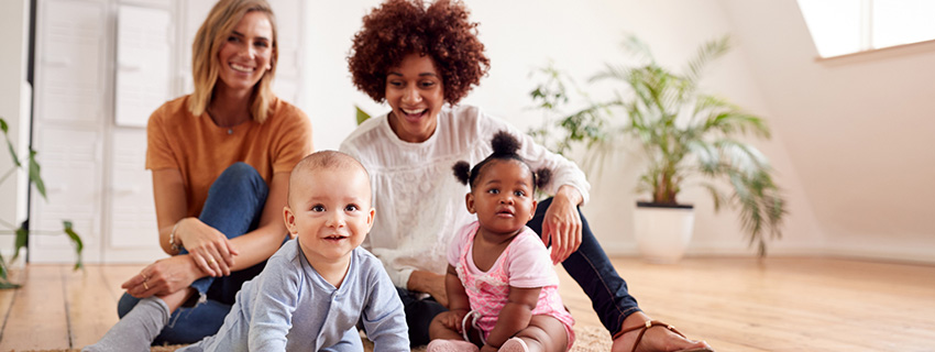 Two women sitting on the floor with their babies