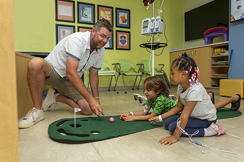 Marc Leishman shares professional golf tips with CHKD patients Bellamy Dixon and Zoey Wrenn Thomas.
