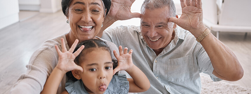 Portrait of smiling mixed race grandparents and granddaughter taking a selfie in the lounge at home