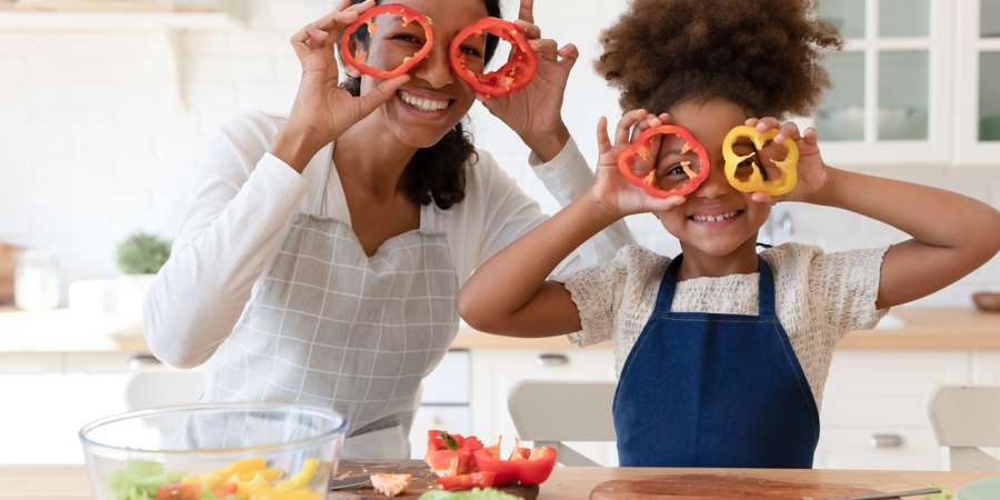 Happy african american family in aprons making funny grimaces with pepper, looking at camera. 