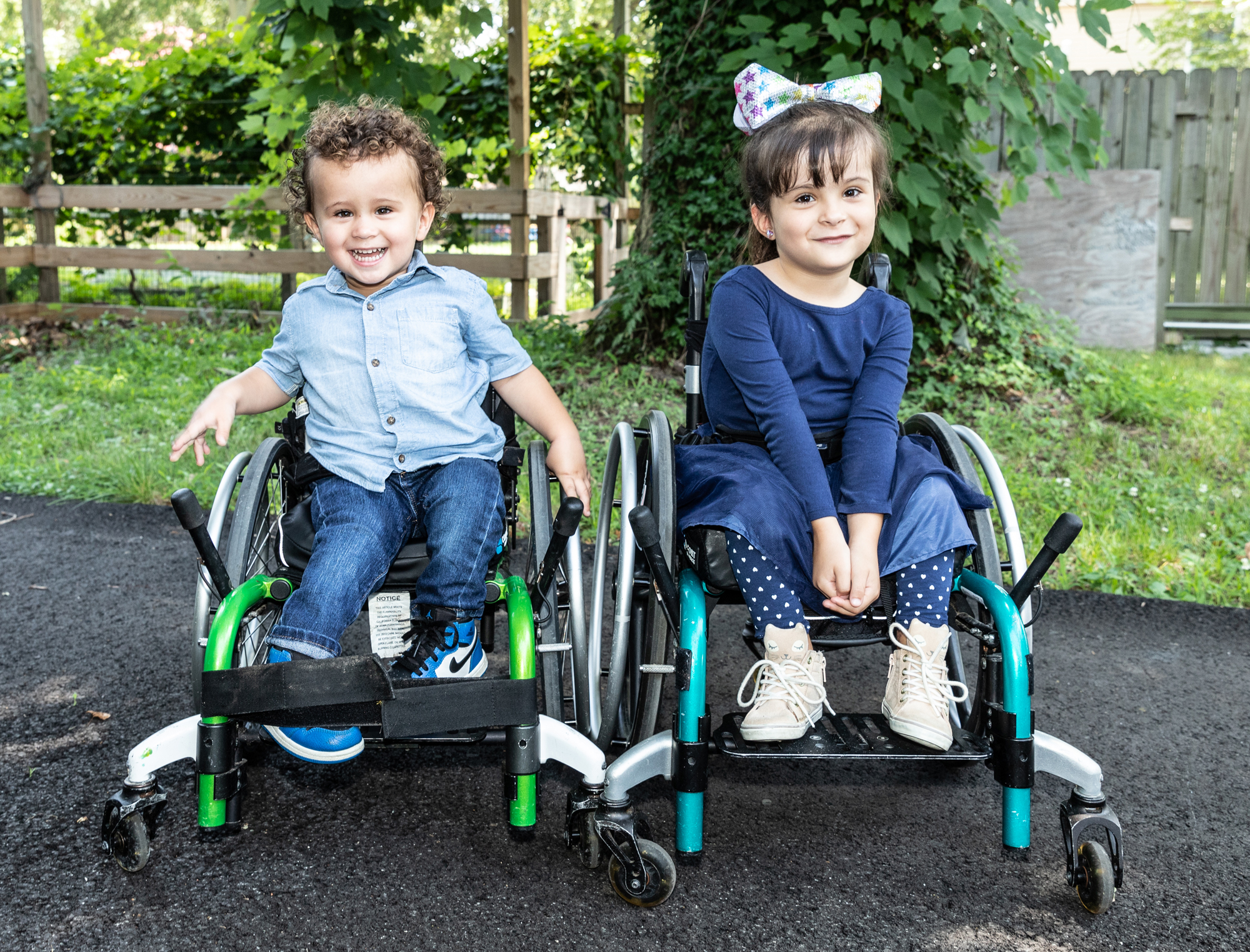 Young siblings with spina bifida smiling in their wheelchairs.