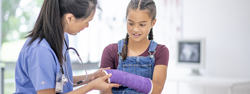 Girl with an arm cast checked by a doctor