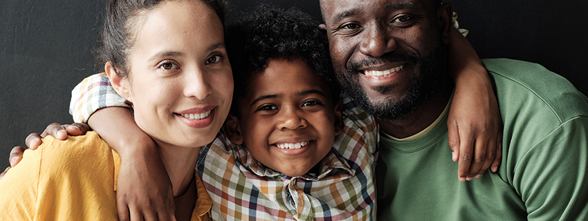 Parents and their child smiling at the camera.