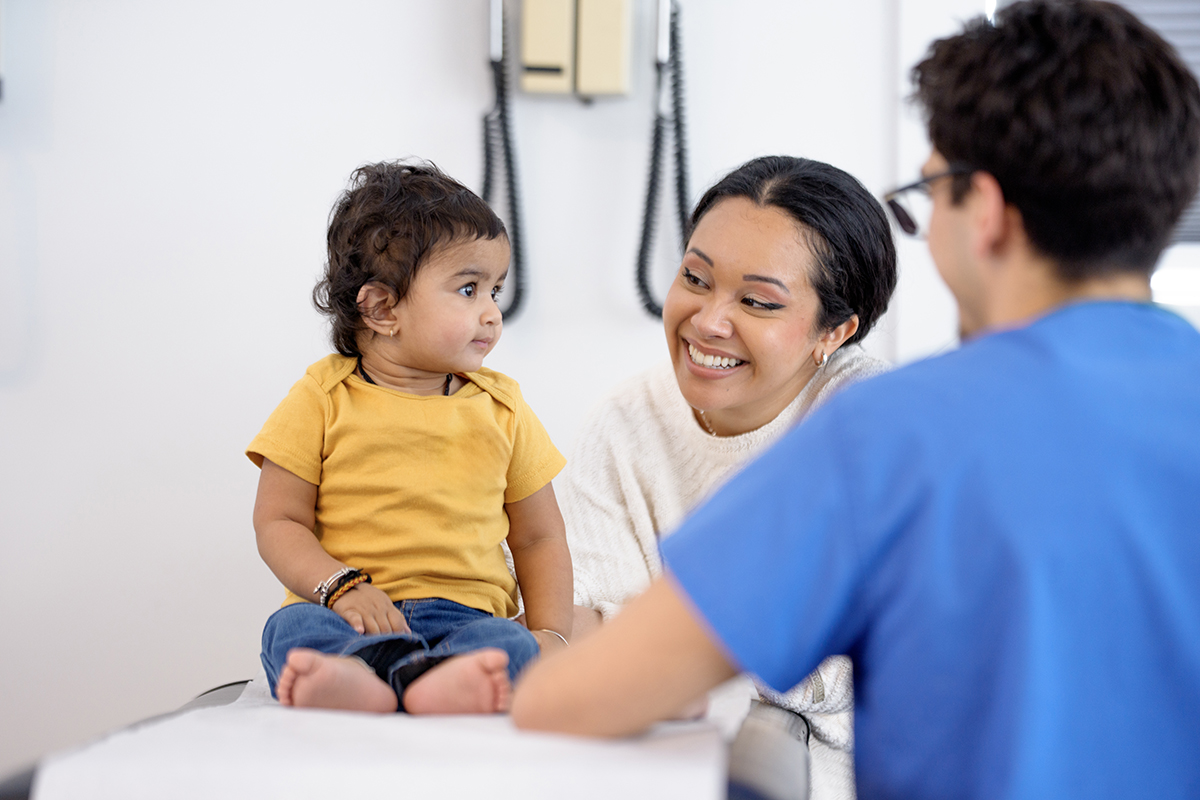  Smiling Pediatric Visit With Mom And Healthcare Professional In Clinic Setting For Checkup
