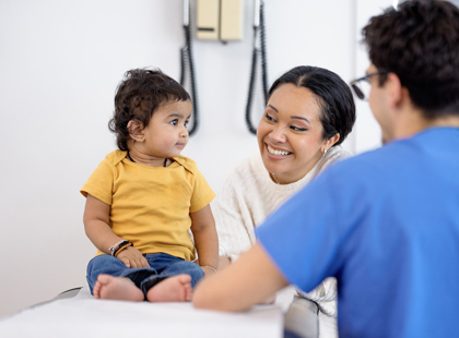 Smiling Pediatric Visit With Mom And Healthcare Professional In Clinic Setting For Checkup