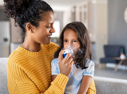 Mom helping child with her asthma inhaler