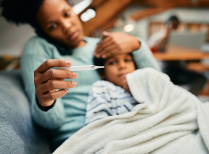 Child blowing her nose while her mother looks concerned.