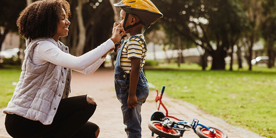 Mom helping her son wear a helmet