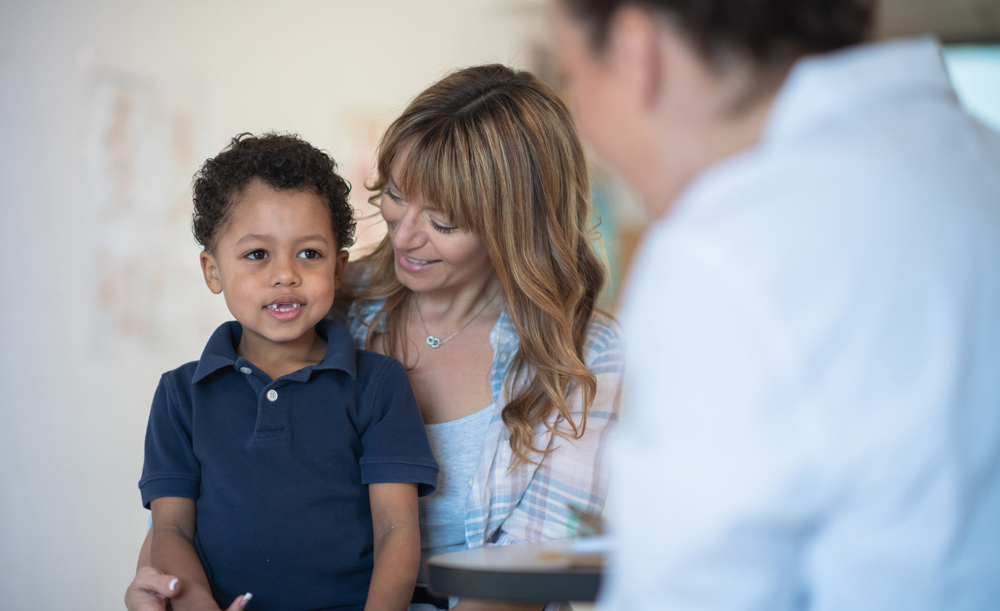 A doctor discusses a routine checkup with a mother and her son.